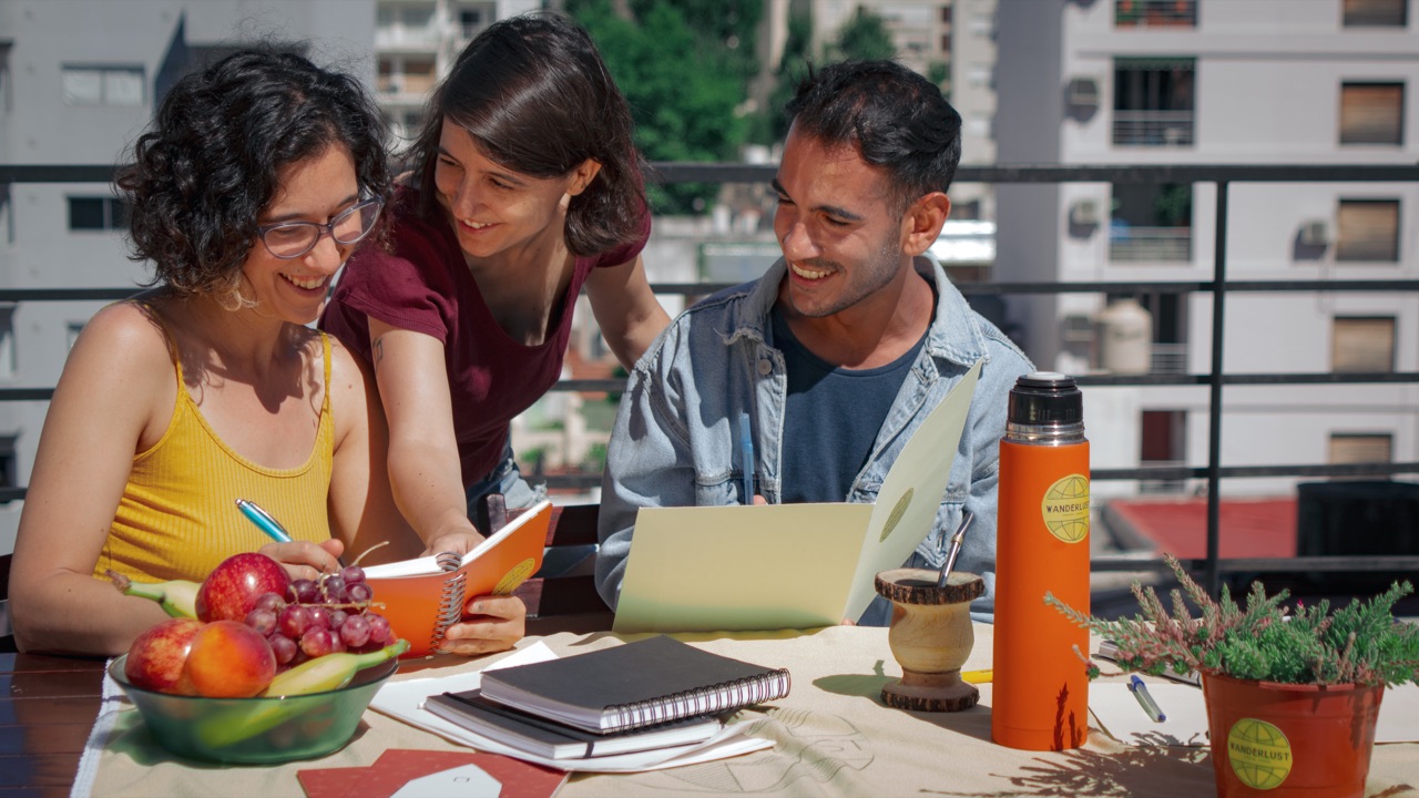 Three adult students studying Spanish together on a rooftop terrace overlooking Buenos Aires
