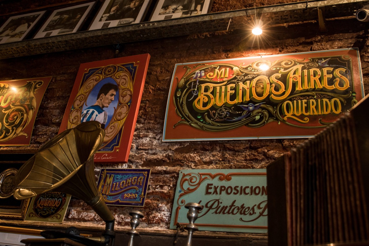 Hand-painted fileteado signs including 'Mi Buenos Aires Querido' on an exposed-brick wall in Buenos Aires